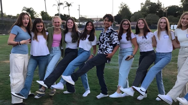 Eine Gruppe von Schülerinnen steht auf einem Grasfeld mit Palmen auf dem Gelände der Mission College Preparatory Catholic High School.