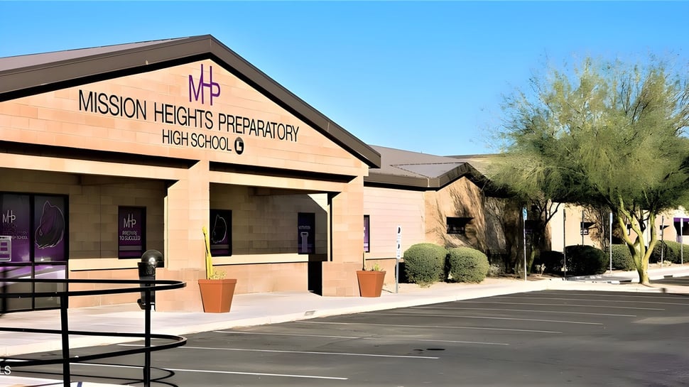 Das Gebäude der Mission Heights Preparatory High School mit Parkplatz im Vordergrund und blauem Himmel im Hintergrund.