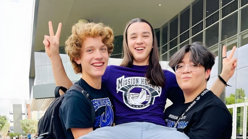 Drei Schülerinnen und Schüler zeigen auf dem Campus der Mission Heights Preparatory High School Friedenszeichen mit den Händen.