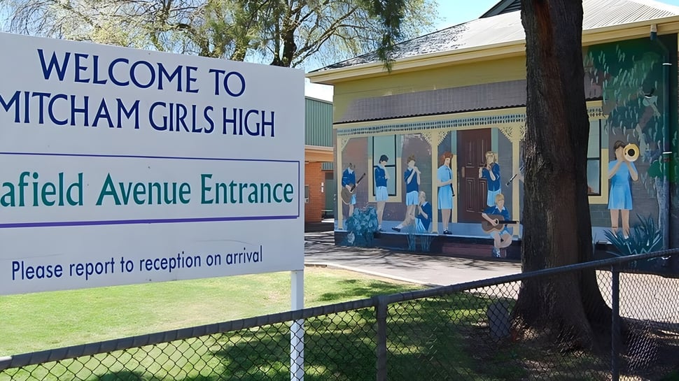 Der Eingang der Mitcham Girls High School mit Willkommensschild, Wandbild und einem Zaun vor einer Rasenfläche.