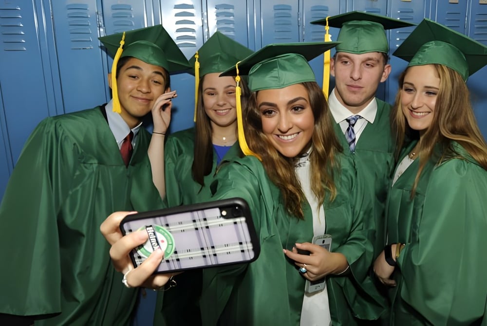 Eine Gruppe von Absolventinnen und Absolventen der Mitchell District High School in grünen Abschlussroben posiert vor blauen Schließfächern.