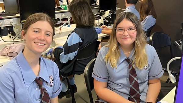 Eine Gruppe Schüler in Schuluniformen steht in einem Klassenraum der Mitchelton State High School.