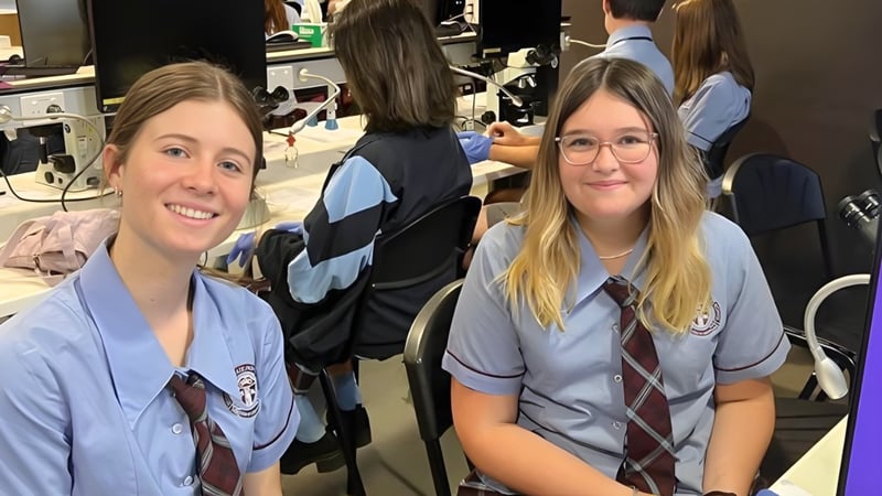 Eine Gruppe Schüler in Schuluniformen steht in einem Klassenraum der Mitchelton State High School.
