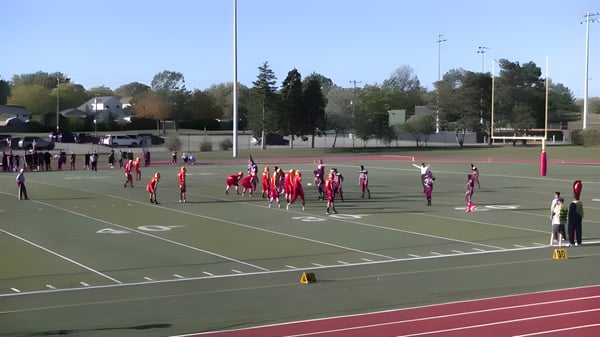 Zwei Teams in roten und weißen Trikots spielen auf dem Sportplatz der M.M. Robinson High School.