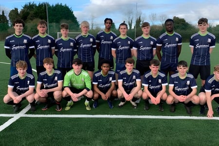 Eine Gruppe junger Fußballspielerinnen und Fußballspieler posiert auf dem Kunstrasen des Moate Community College.