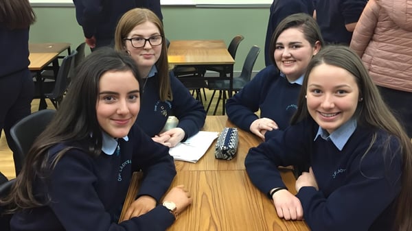 Eine Gruppe von Schülerinnen sitzt gemeinsam an einem Tisch im Klassenraum des Moate Community College und unterhält sich.