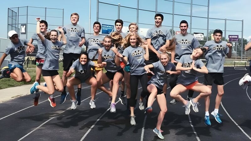 Eine Gruppe Schüler in Sportkleidung posiert gemeinsam auf einem Sportplatz auf dem Campus der Monarch High School.