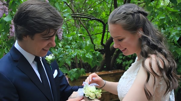 Ein Paar in formeller Kleidung steht im grünen Außenbereich des Monarch Park Collegiate Institute und schaut sich an.