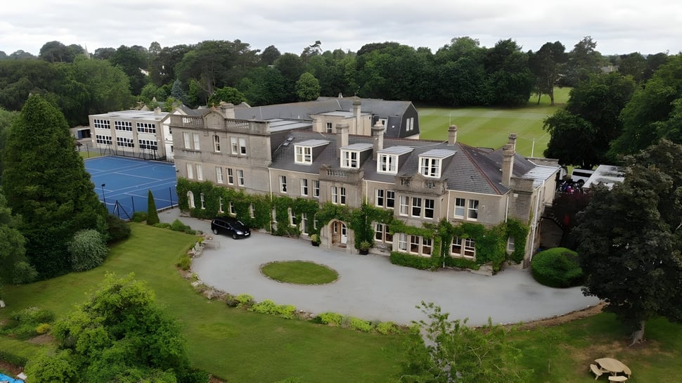 Das historische Haupthaus der Monkton Combe School ist von gepflegtem Grün und einem Rundweg umgeben.