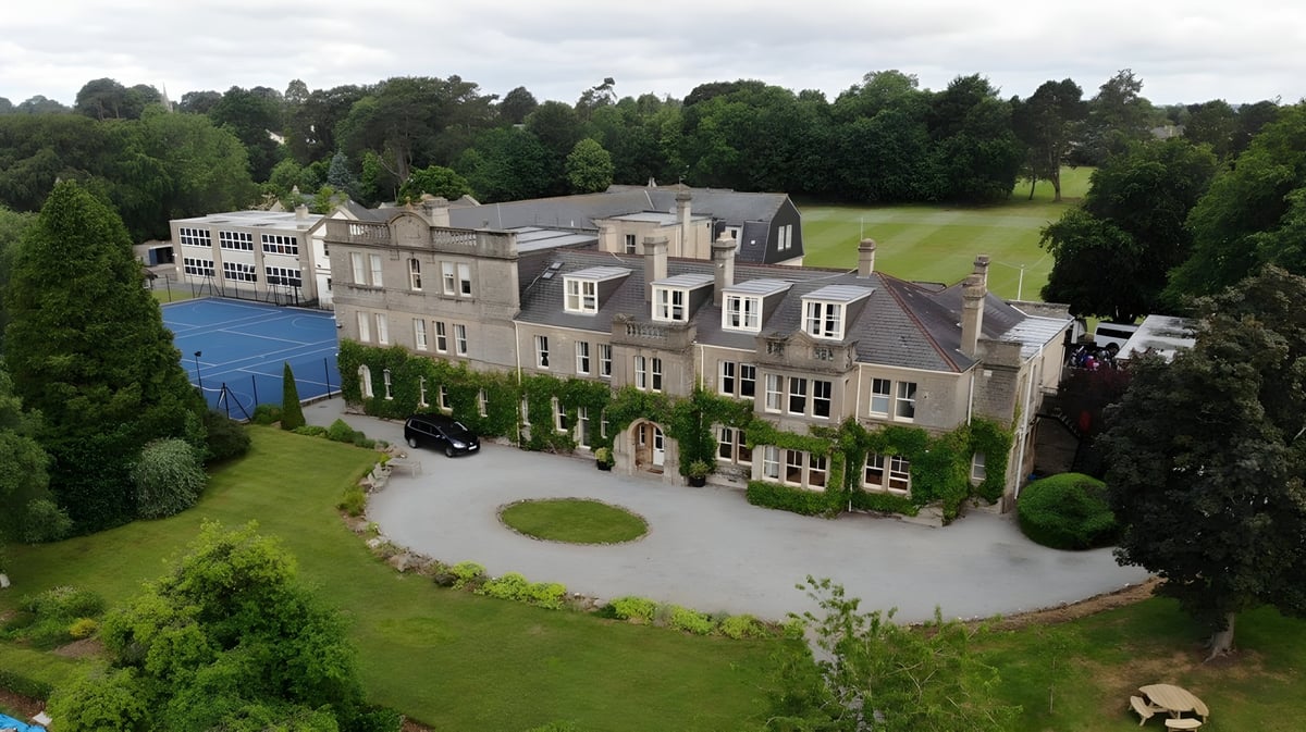 Das historische Haupthaus der Monkton Combe School ist von gepflegtem Grün und einem Rundweg umgeben.