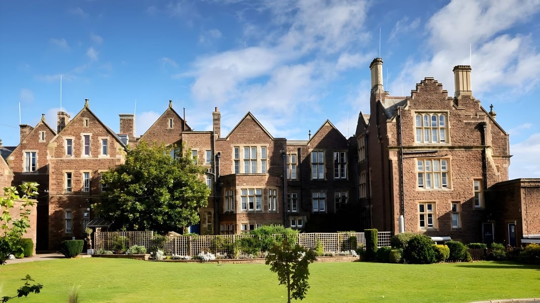 Das historische Gebäude der Monmouth School for Boys ist von gepflegtem Rasen und grüner Vegetation umgeben.