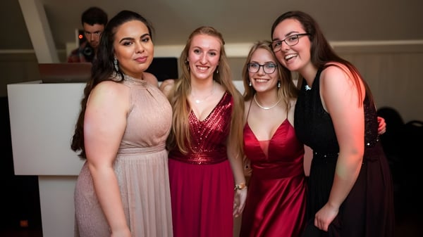 Vier Schülerinnen der Monmouth School for Girls posieren in festlicher Kleidung und lächeln gemeinsam.