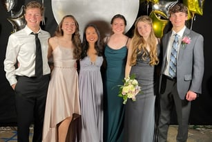 Eine Gruppe von sechs Personen in formeller Kleidung posiert vor einer Kulisse mit metallic Luftballons auf dem Campus der Monsignor Donovan Catholic High School.