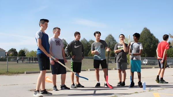 Eine Gruppe Schülerinnen und Schüler steht gemeinsam auf dem Sportplatz der Monsignor Doyle Catholic Secondary School.