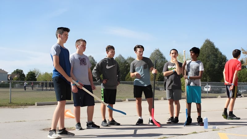 Eine Gruppe Schülerinnen und Schüler steht gemeinsam auf dem Sportplatz der Monsignor Doyle Catholic Secondary School.