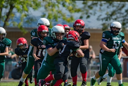 Eine Gruppe junger Fußballspieler steht auf dem Spielfeld der Montcalm Secondary School mit Bäumen im Hintergrund.
