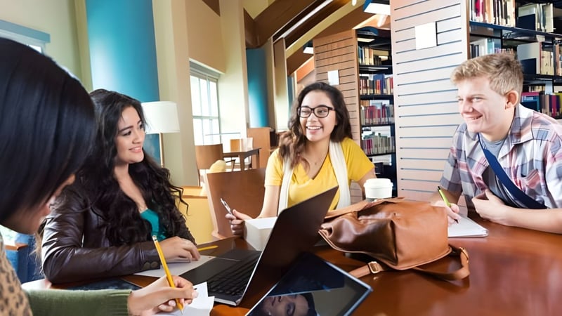 Eine Gruppe Schülerinnen und Schüler der Montcalm Secondary School arbeitet gemeinsam mit Laptops in einem Studienbereich.