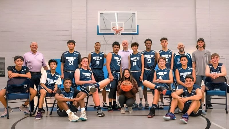 Eine Gruppe von Schülern der Monterey Bay Academy posiert gemeinsam in der Sporthalle vor einem Basketballkorb.