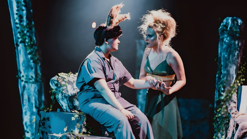 Zwei Personen umarmen sich auf der Bühne bei Montpelier High School vor einer Kulisse aus üppigem Laubwerk und Bühnenlicht.