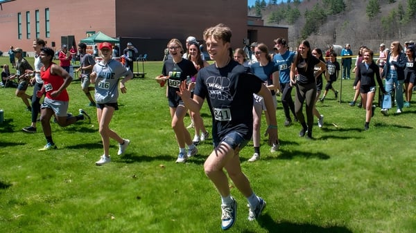 Eine Gruppe von Schülerinnen und Schülern versammelt sich auf einem Sportfeld vor einem Backsteingebäude der Montpelier Roxbury Public School District.
