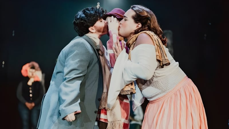 Schüler des Montpelier Roxbury Public School District führen auf einer dunklen Bühne eine Theaterszene mit einer Umarmung und einem Kuss auf.