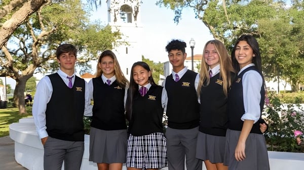 Eine Gruppe von Schülerinnen und Schülern posiert in Schuluniformen vor dem Campusgebäude mit Glockenturm der Montverde Academy.