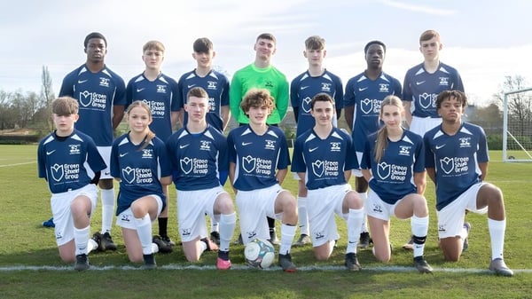 Eine Gruppe von Schülerinnen und Schülern der Moorland School posiert gemeinsam auf einem Fußballfeld.