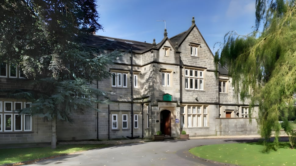Das Tudor-Gebäude der Moorland School steht umgeben von einer grünen Landschaft mit einem Weg zum Eingang.
