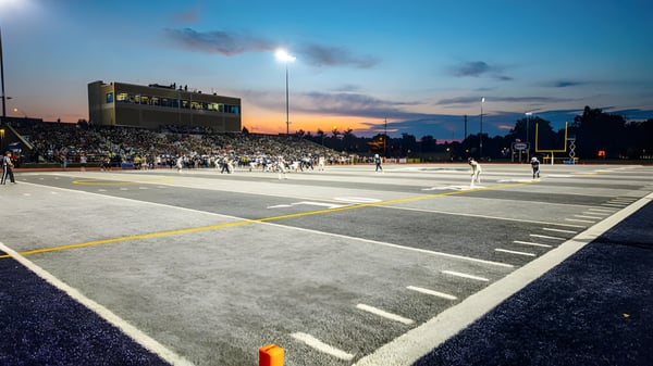 Das Footballfeld der Morgan High School ist bei Sonnenuntergang mit Zuschauern im Stadium zu sehen.