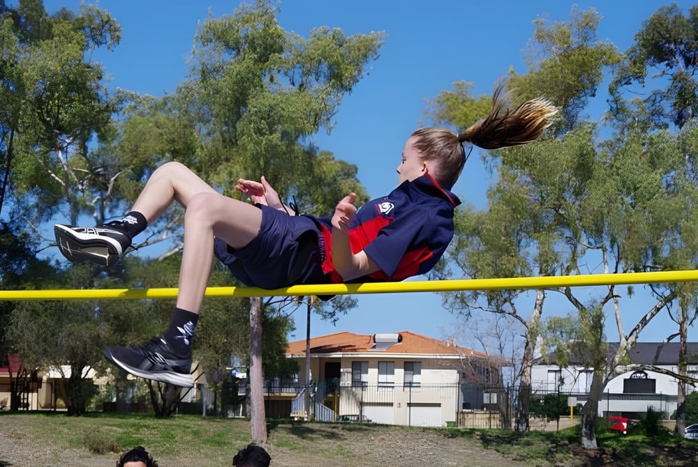 Ein junger Athlet führt einen Hochsprung auf dem Sportplatz der Morley Senior High School aus.