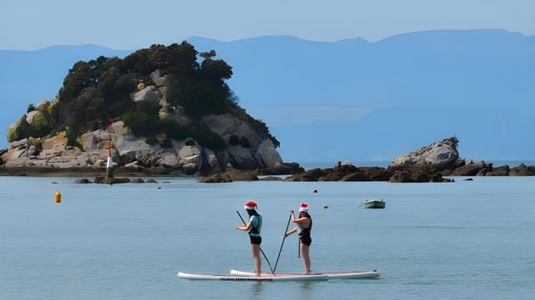 Zwei Personen stehen auf Paddleboards auf einem ruhigen Gewässer vor der bergigen Landschaft bei der Motueka High School.