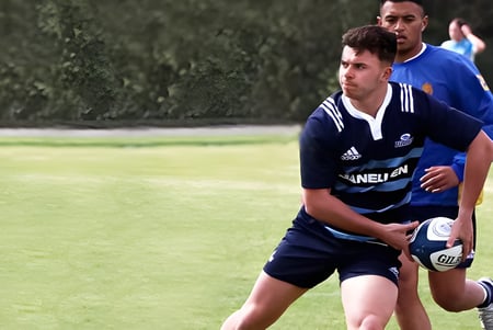 Ein Schüler von Mount Albert Grammar hält einen Rugbyball auf einem grasbewachsenen Spielfeld.
