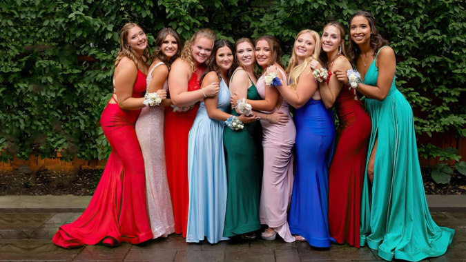 Eine Gruppe von Schülerinnen der Mount Anville Secondary School steht in farbigen Kleidern vor grüner Pflanzenkulisse.