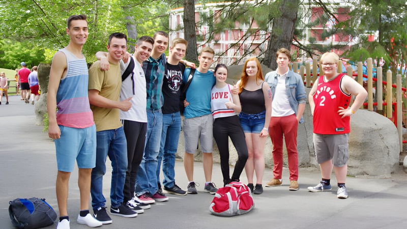Eine Gruppe Schüler steht auf der Straße vor Gebäuden und Bäumen auf dem Campus der Mount Baker Secondary School.