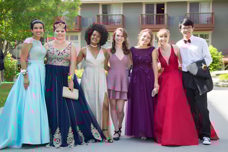 Schülerinnen der Mount Baker Secondary School stehen in formeller Kleidung gemeinsam in einem Garten vor einem Gebäude.