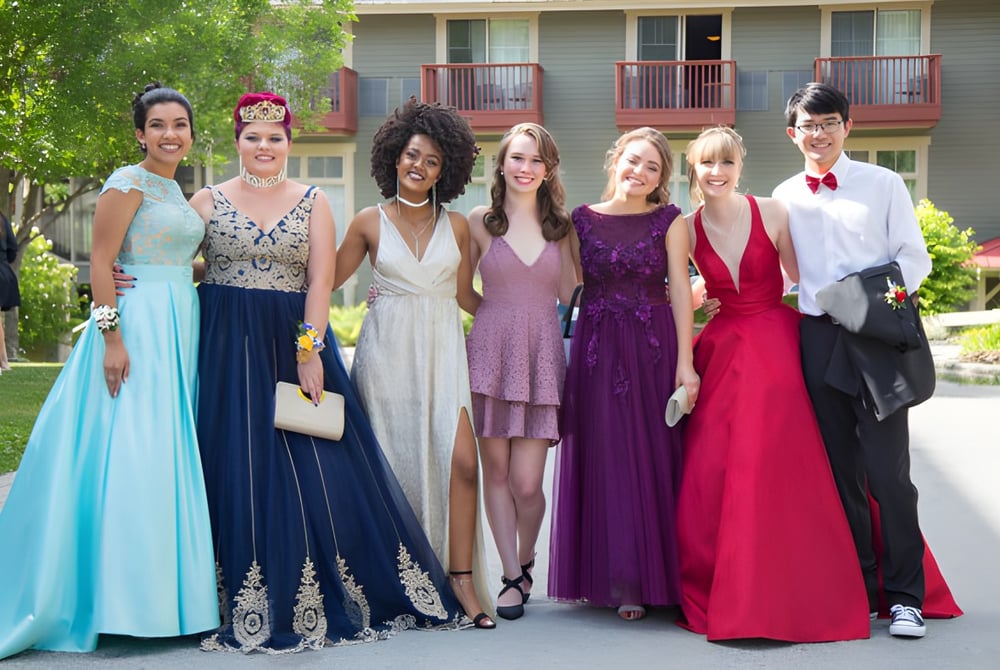 Schülerinnen der Mount Baker Secondary School stehen in formeller Kleidung gemeinsam in einem Garten vor einem Gebäude.