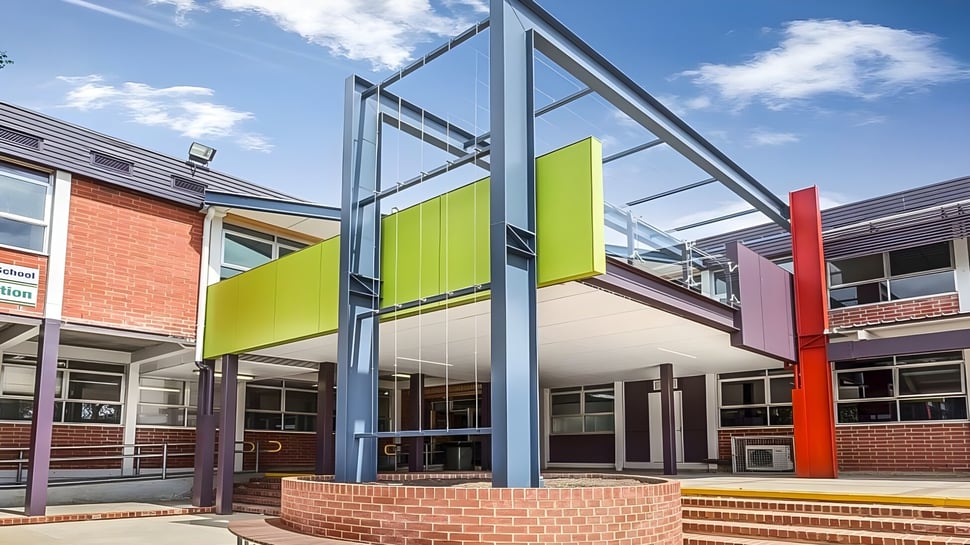 Das moderne, mehrfarbige Gebäude der Mount Barker High School ist mit Glas- und Stahlstrukturen vor blauem Himmel zu sehen.