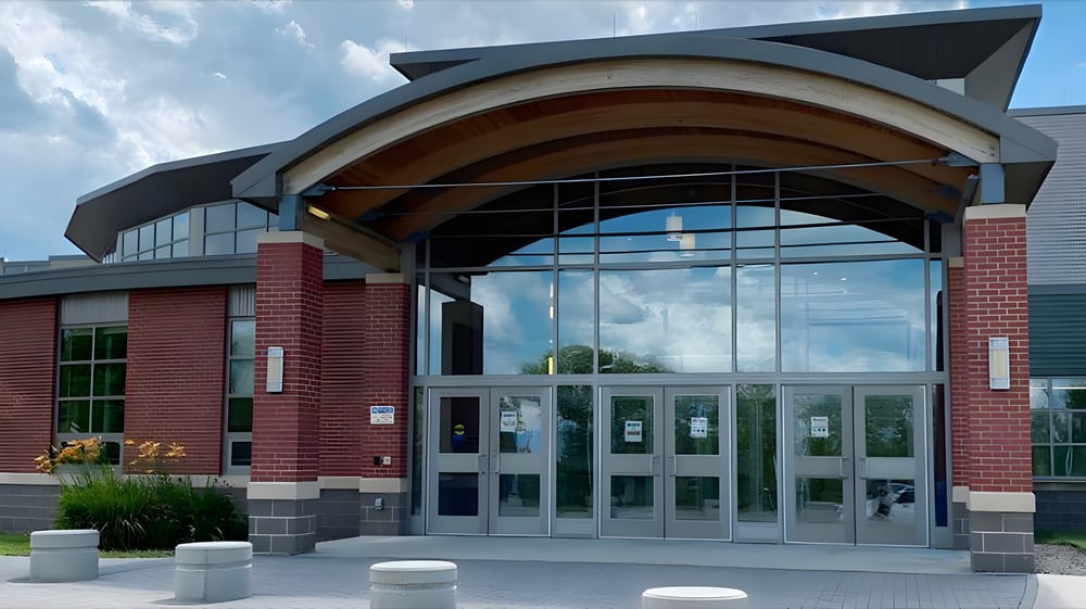 Das moderne Gebäude mit Glasfassade und geschwungenem Holzdach steht auf dem Campus der Mount Blue High School.
