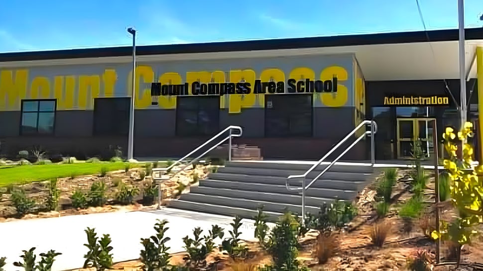 Das Gebäude der Mount Compass Area School mit großem gelbem Schild und Treppe zum Eingang ist zu sehen.