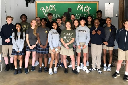 Eine Gruppe Schüler der Mount De Sales Academy steht vor einem Schild mit der Aufschrift Back Pack.
