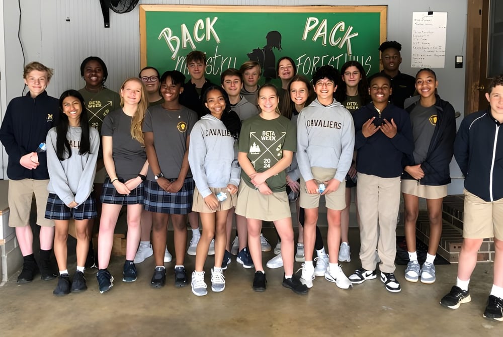 Eine Gruppe Schüler der Mount De Sales Academy steht vor einem Schild mit der Aufschrift Back Pack.