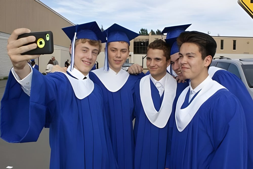Eine Gruppe junger Männer in blauen Abschlussroben macht ein Selfie auf dem Gelände der Mount Elizabeth Middle/Secondary School.