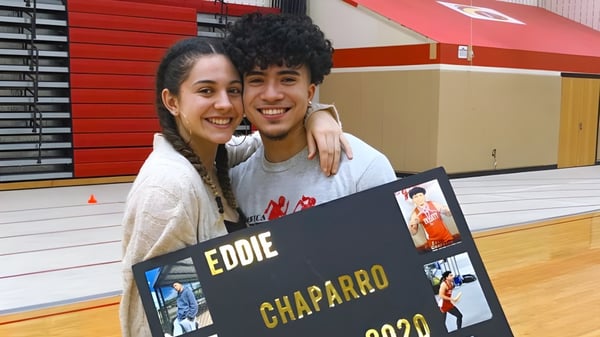 Ein junges Paar posiert gemeinsam vor einem Poster mit dem Namen Eddie Chaparro auf dem Campus der Mount Everett Regional High School.