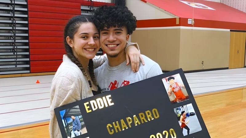 Ein junges Paar posiert gemeinsam vor einem Poster mit dem Namen Eddie Chaparro auf dem Campus der Mount Everett Regional High School.