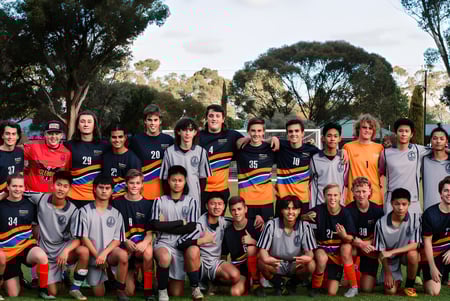 Eine Gruppe junger Fußballspielerinnen und Fußballspieler posiert im Park auf dem Gelände der Mount Gambier High School.