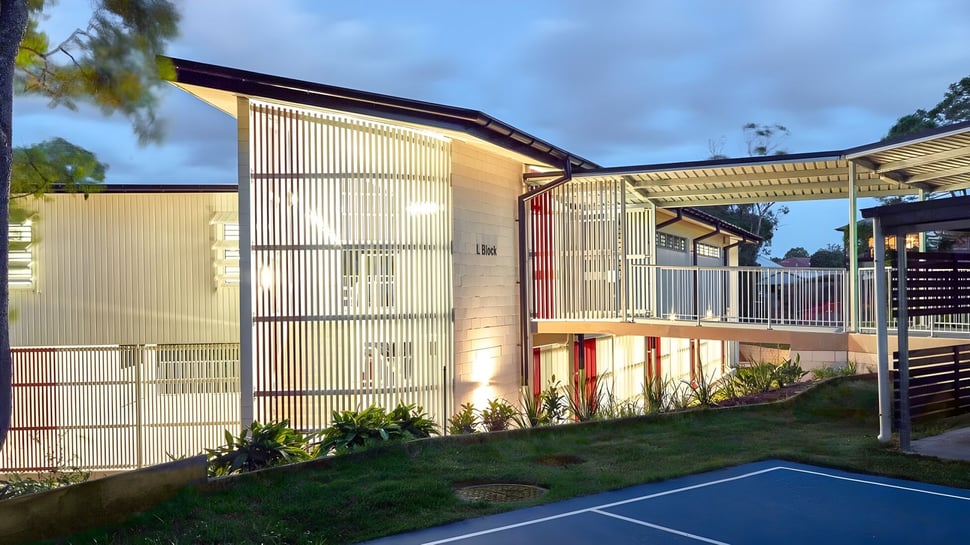 Das moderne mehrstöckige Gebäude der Mount Gravatt State High School mit einer Metallfassade und einer grasbewachsenen Fläche im Vordergrund.