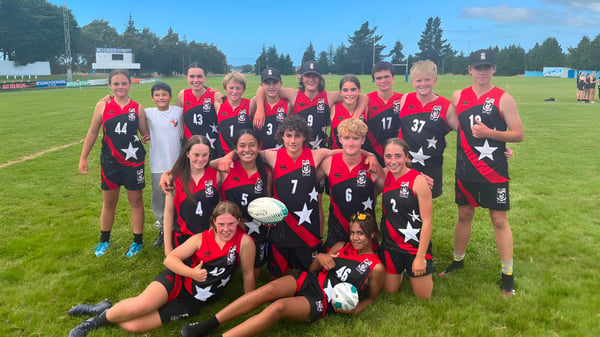 Eine Gruppe weiblicher Fußballspielerinnen im roten und schwarzen Trikot steht auf einem Spielfeld auf dem Campus des Mount Hutt College.