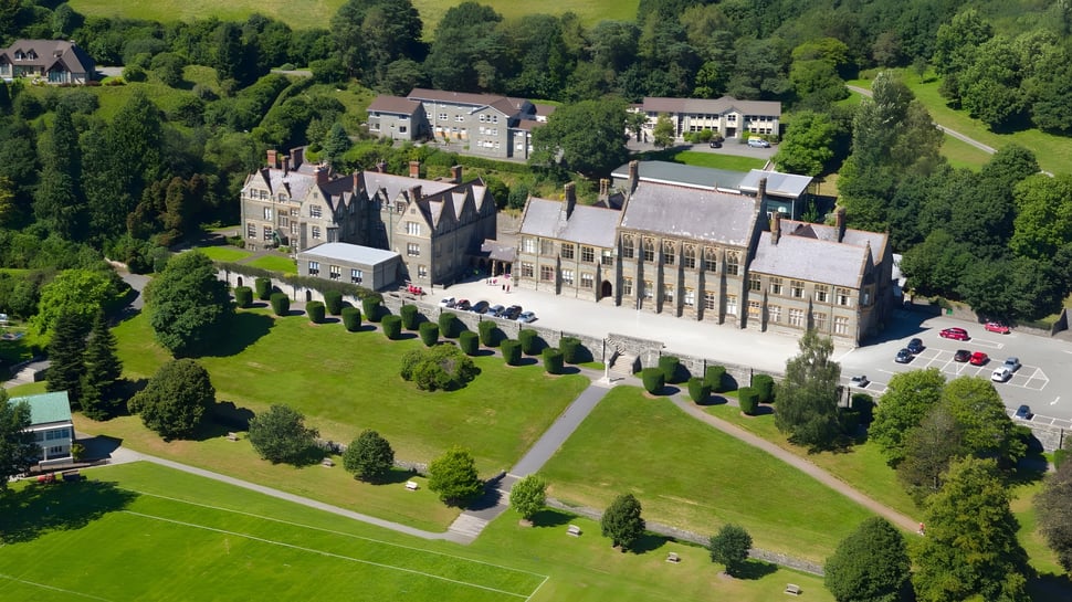Ein mittelalterlich anmutendes Schloss auf einem grasbewachsenen Hügel umgeben von Bäumen auf dem Gelände der Mount Kelly School.