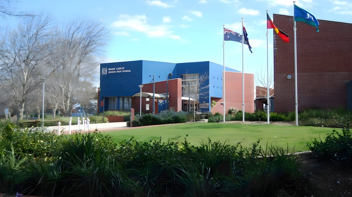 Das moderne Schulgebäude der Mount Lawley Senior High School steht in einer gepflegten Grünanlage mit Bäumen und internationalen Flaggen.