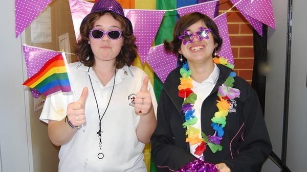 Zwei Schülerinnen der Mount Lawley Senior High School posieren vor einer bunt mit Regenbogenflaggen dekorierten Kulisse.